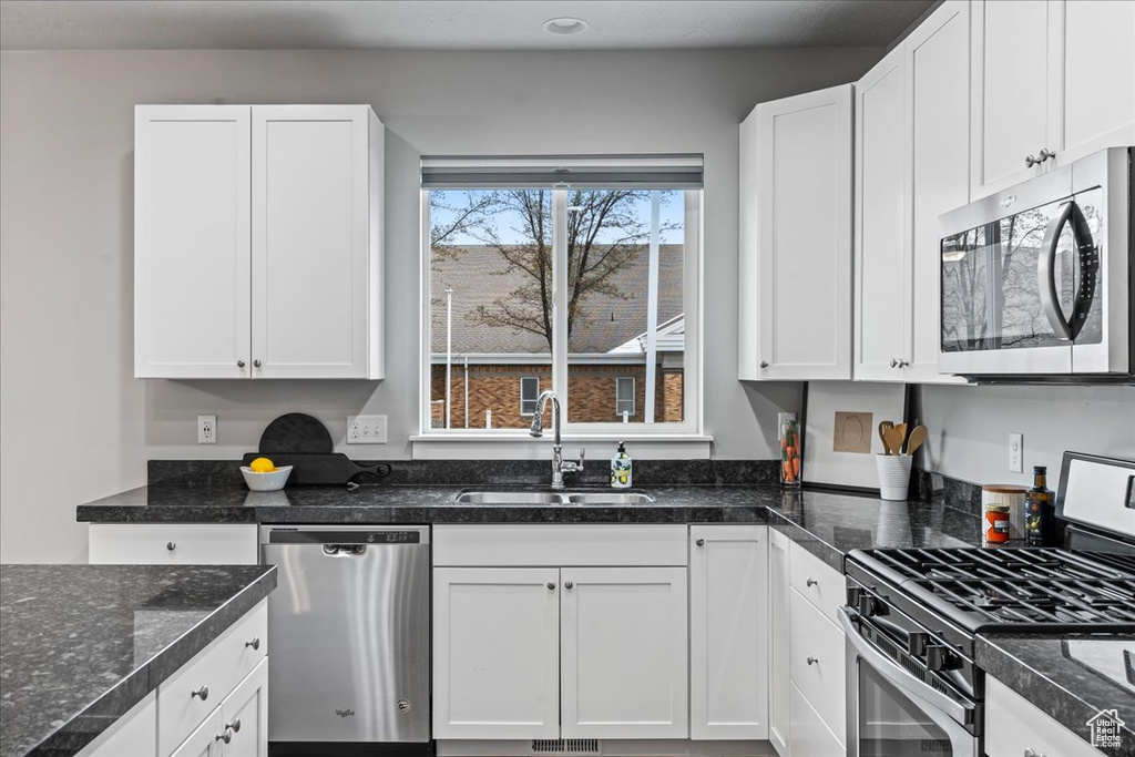 Kitchen with appliances with stainless steel finishes, sink, plenty of natural light, and white cabinetry