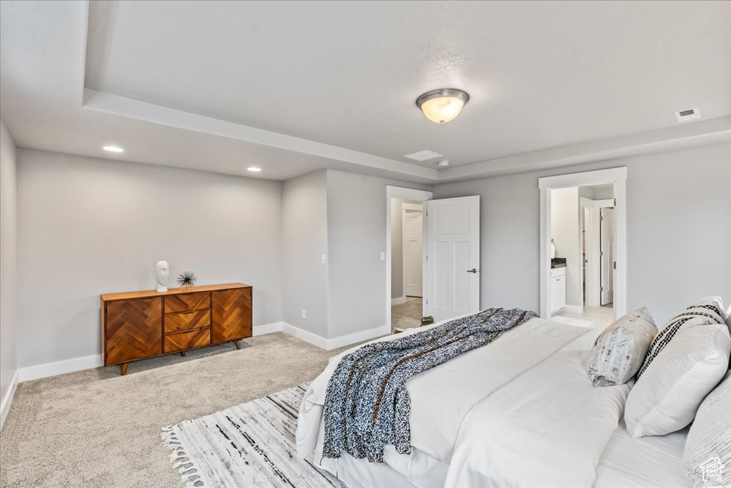 Bedroom with connected bathroom and light colored carpet
