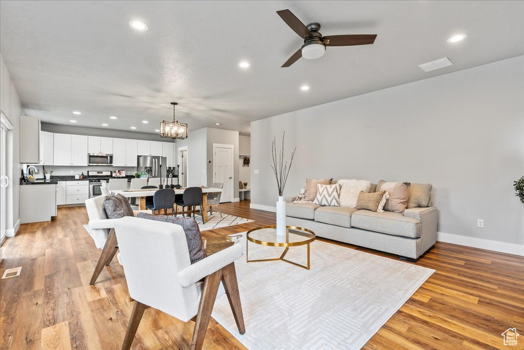 Living room featuring sink, ceiling fan with notable chandelier, and light hardwood / wood-style floors