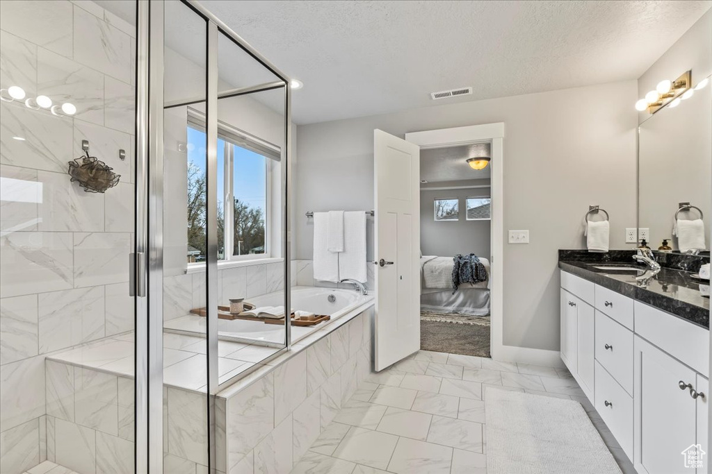 Bathroom with plus walk in shower, a textured ceiling, tile floors, and oversized vanity