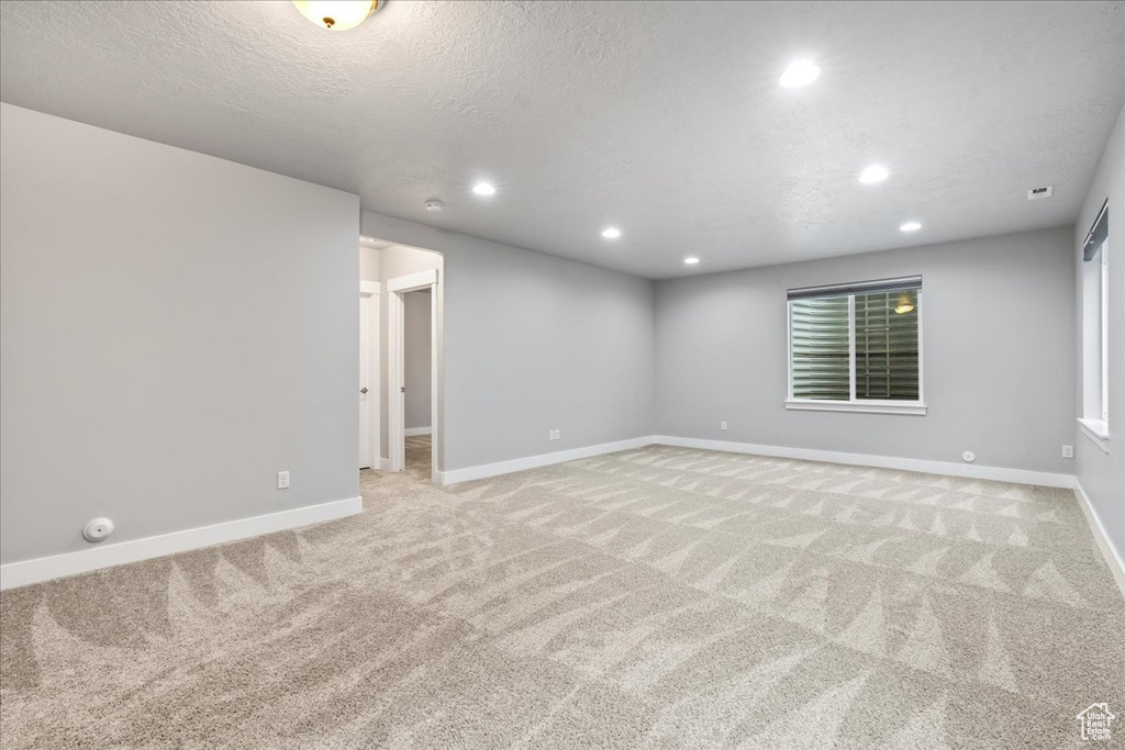 Empty room with light carpet and a textured ceiling