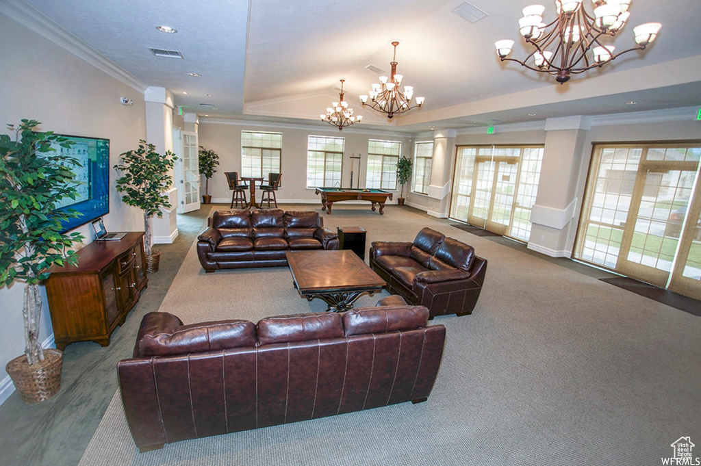 Carpeted living room featuring a tray ceiling, crown molding, an inviting chandelier, and pool table