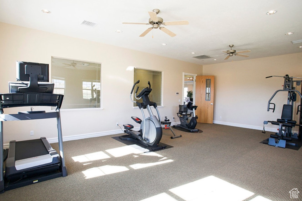 Workout room with ceiling fan and dark colored carpet