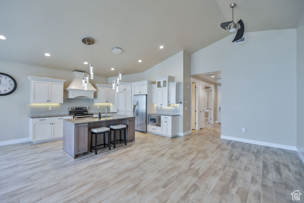 Kitchen featuring light hardwood / wood-style flooring, custom range hood, stainless steel appliances, and white cabinetry