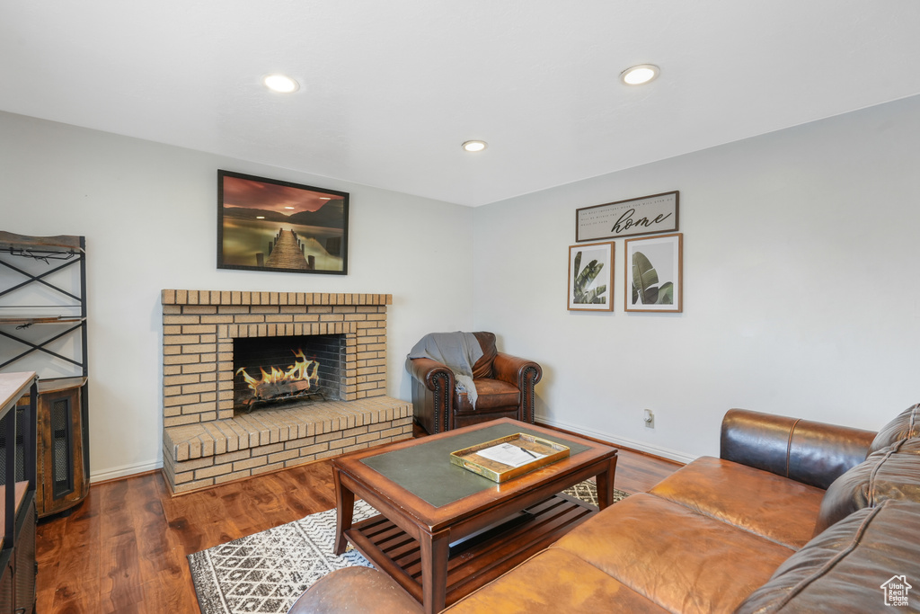 Living room with dark hardwood / wood-style flooring and a brick fireplace