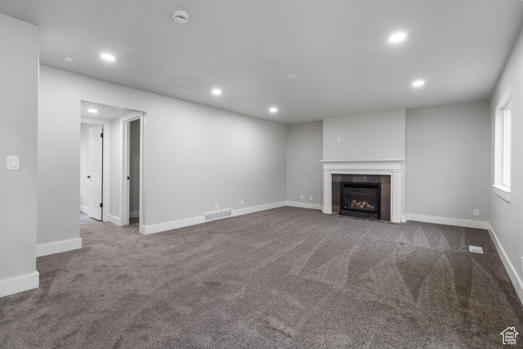 Unfurnished living room featuring a fireplace and dark carpet