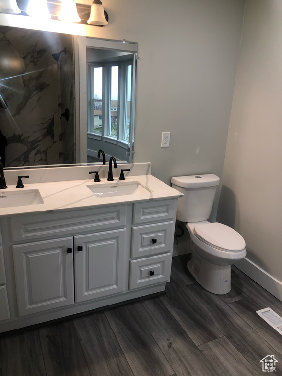 Bathroom with double sink, hardwood / wood-style floors, toilet, and oversized vanity