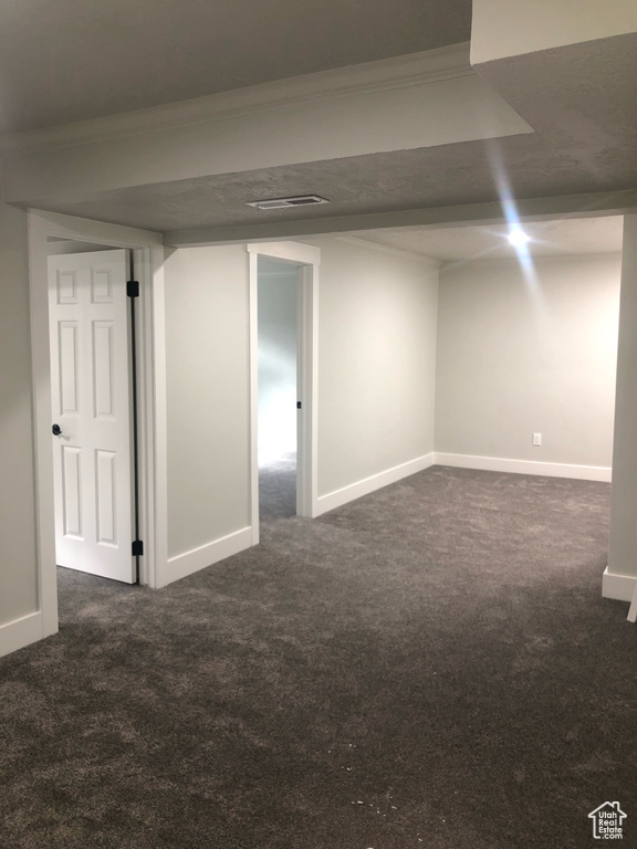 Basement featuring dark carpet and crown molding