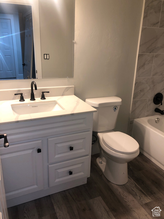 Full bathroom featuring tiled shower / bath, vanity, toilet, and wood-type flooring