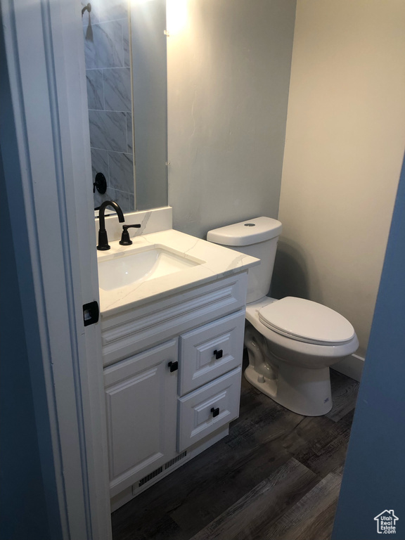 Bathroom with wood-type flooring, vanity, and toilet