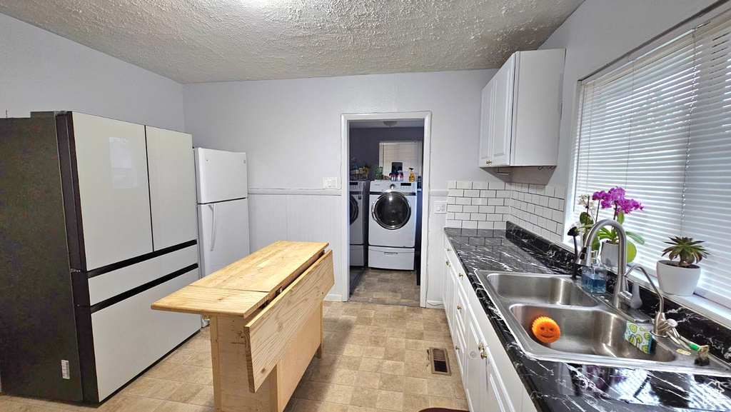Kitchen featuring independent washer and dryer, white cabinets, and white refrigerator