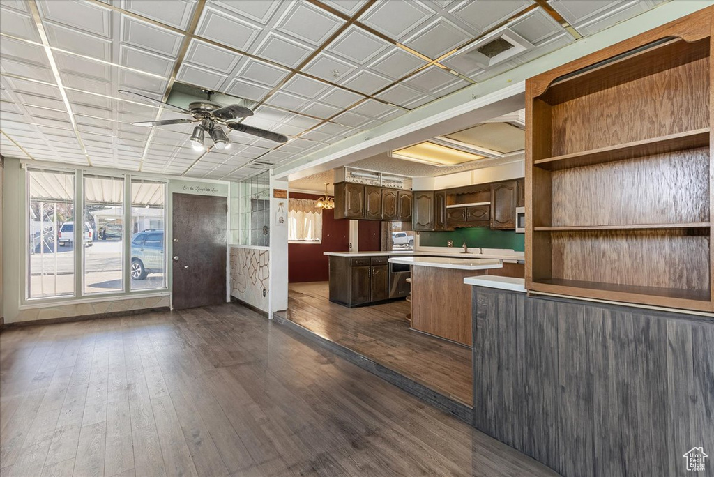 Kitchen with dark brown cabinets, ceiling fan with notable chandelier, dark wood-type flooring, and a center island