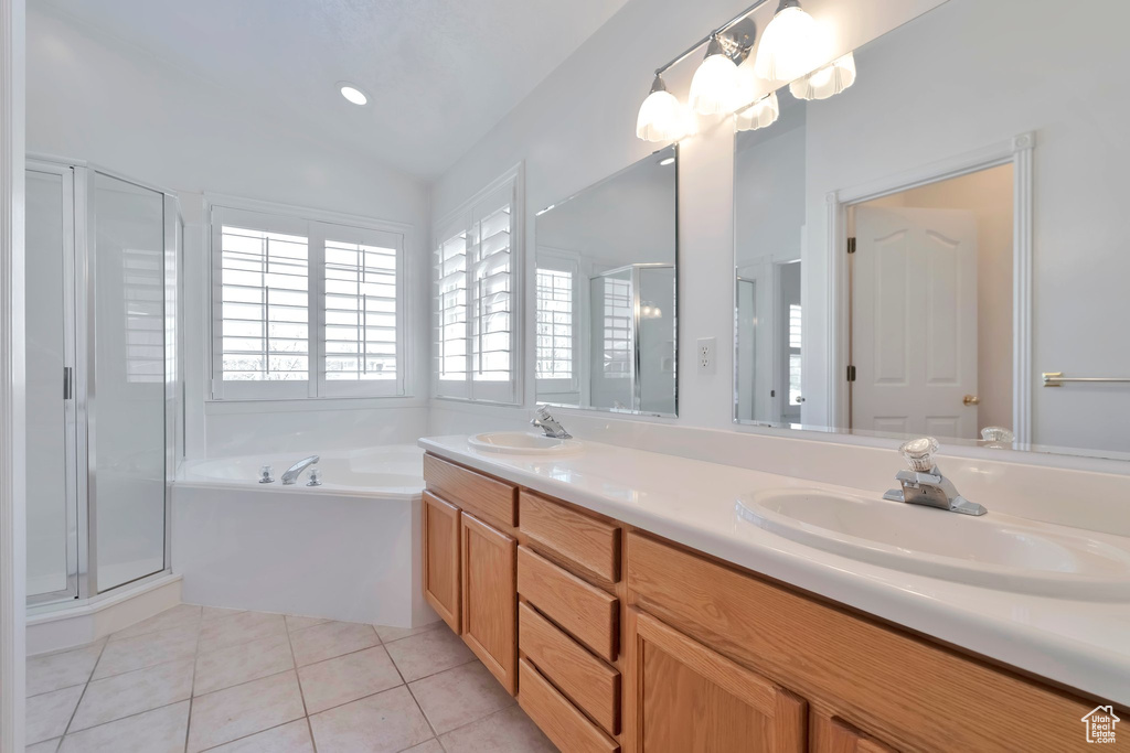 Bathroom featuring large vanity, lofted ceiling, dual sinks, shower with separate bathtub, and tile floors
