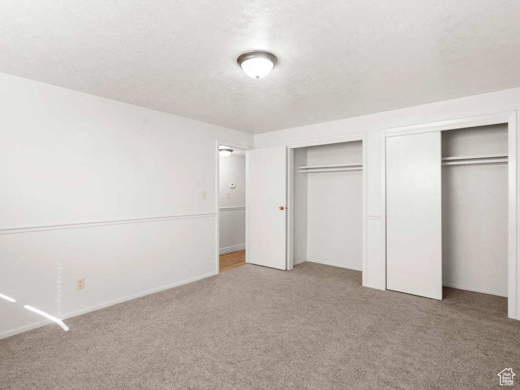 Unfurnished bedroom with light carpet and multiple closets