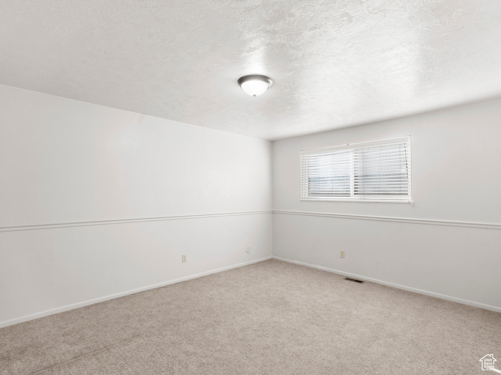 Empty room with a textured ceiling and light colored carpet