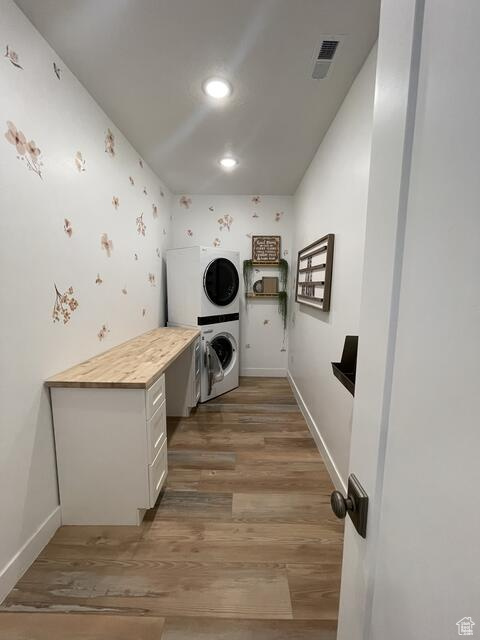 Interior space with wood-type flooring and stacked washer / dryer