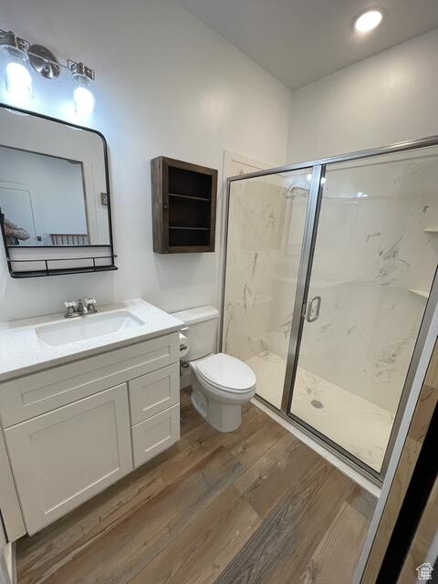 Bathroom with a shower with shower door, toilet, oversized vanity, and hardwood / wood-style flooring