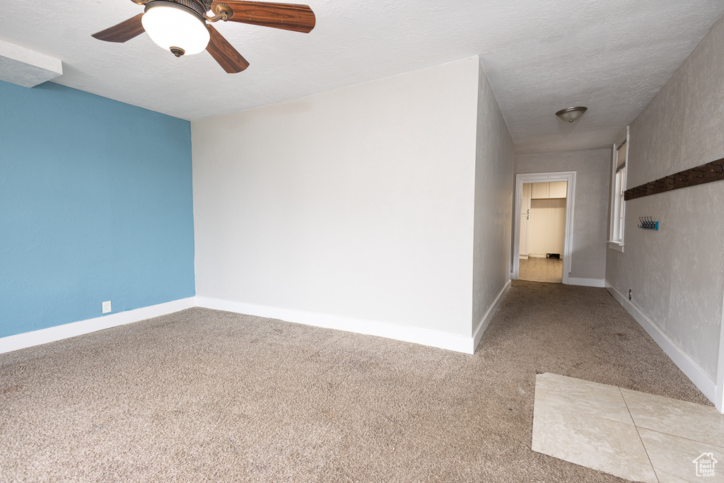 Unfurnished room featuring ceiling fan, a textured ceiling, and light colored carpet