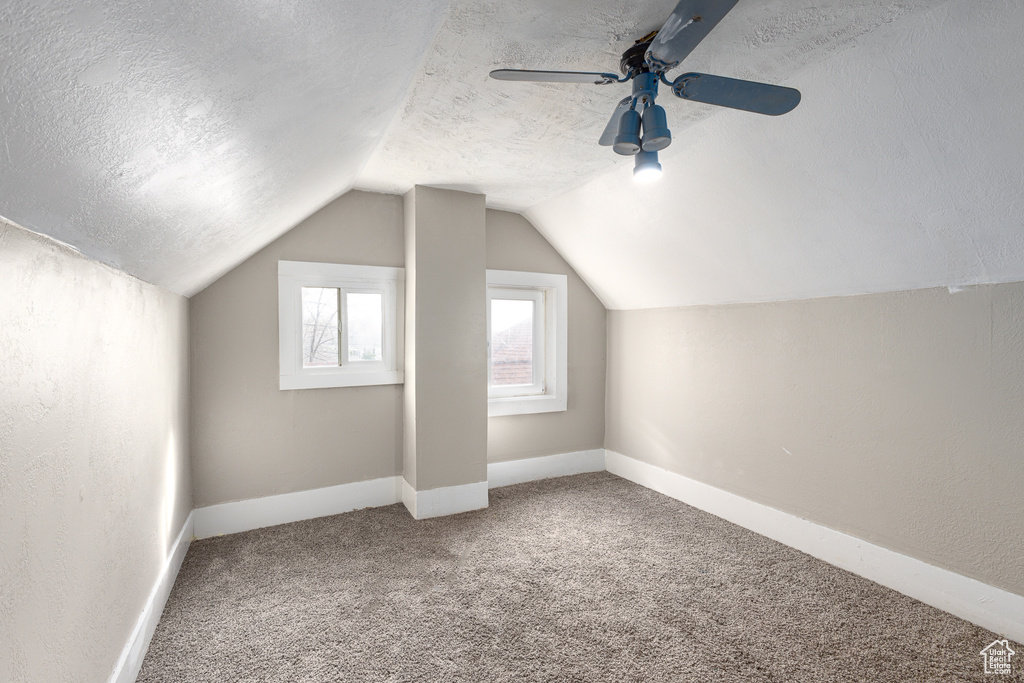 Bonus room with carpet flooring, ceiling fan, lofted ceiling, and a textured ceiling