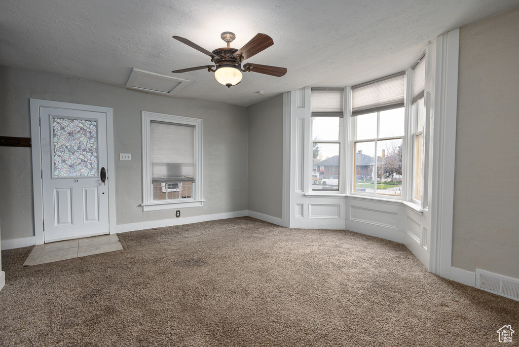 Unfurnished room featuring dark carpet, a textured ceiling, and ceiling fan
