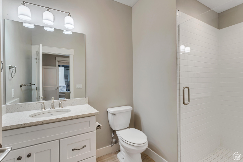 Bathroom featuring a shower with shower door, toilet, and vanity with extensive cabinet space