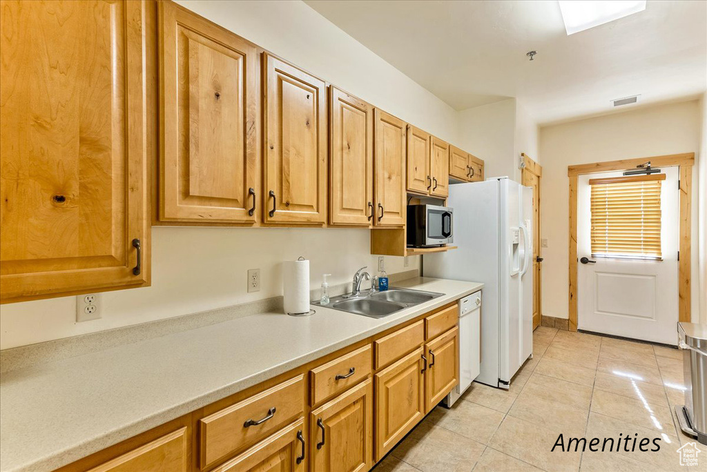 Kitchen featuring dishwasher, sink, stainless steel microwave, and light tile flooring