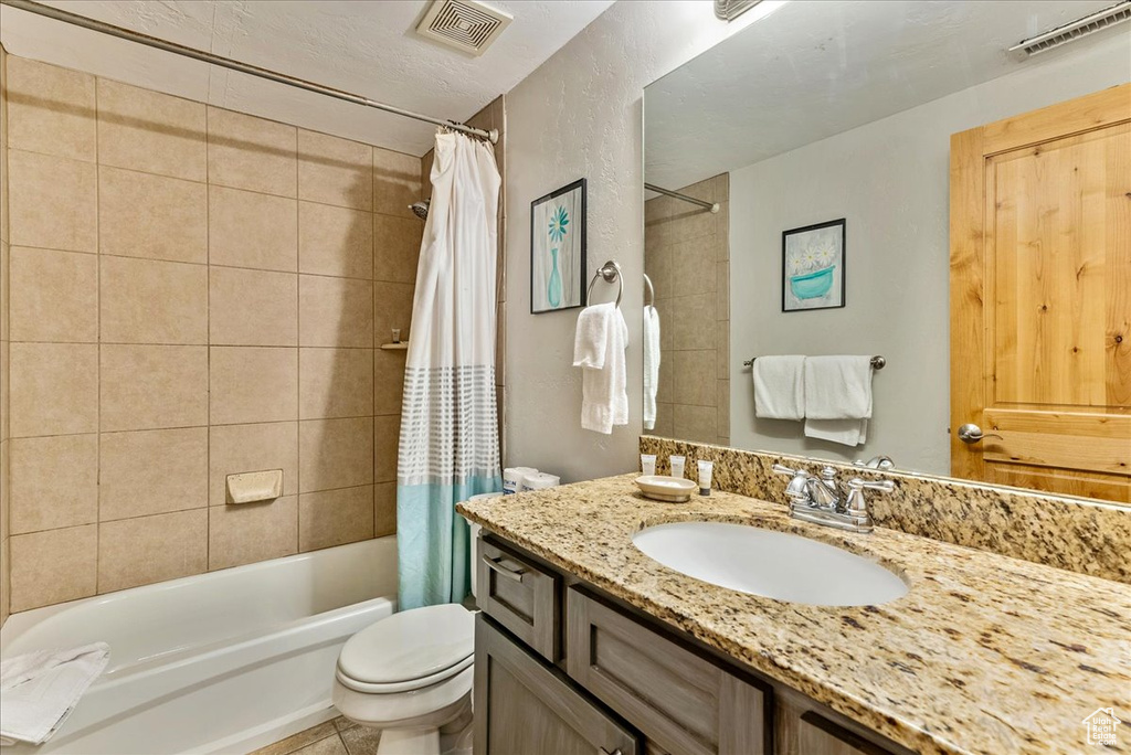 Full bathroom with tile floors, vanity, shower / bath combo with shower curtain, and toilet