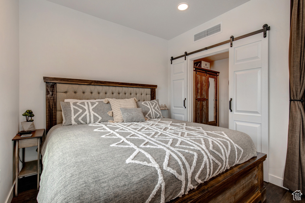 Bedroom featuring dark hardwood / wood-style flooring and a barn door