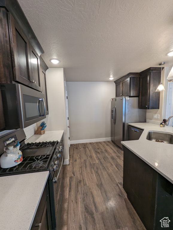 Kitchen with black appliances, pendant lighting, sink, dark brown cabinetry, and dark hardwood / wood-style flooring