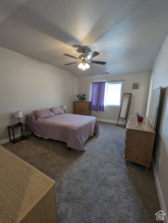 Bedroom with ceiling fan, a textured ceiling, and dark carpet