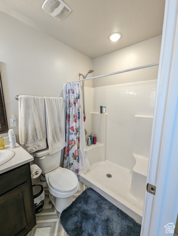 Bathroom with a shower with curtain, vanity, and toilet