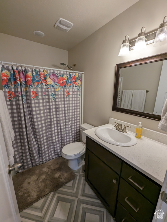 Bathroom featuring vanity with extensive cabinet space, tile flooring, and toilet