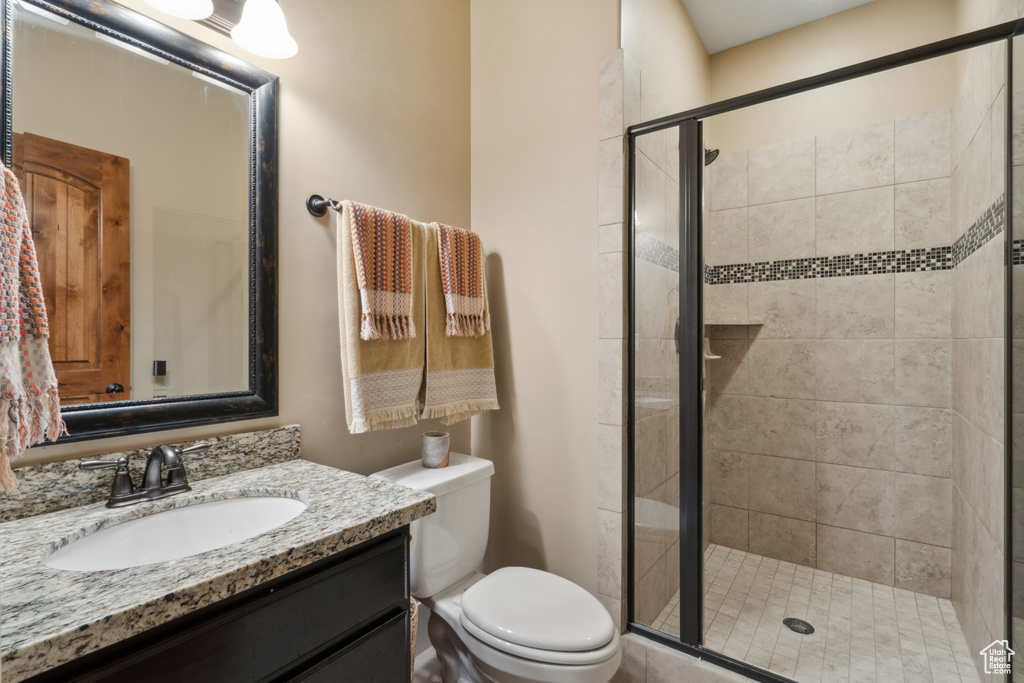 Bathroom featuring toilet, walk in shower, and vanity with extensive cabinet space