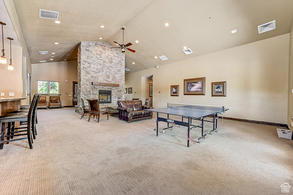 Rec room featuring light carpet, high vaulted ceiling, ceiling fan, and a fireplace