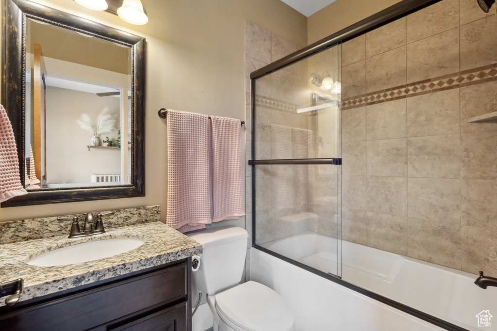 Full bathroom featuring vanity with extensive cabinet space, enclosed tub / shower combo, and toilet