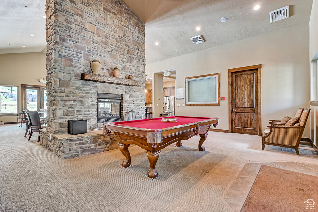 Rec room with billiards, light carpet, high vaulted ceiling, and a stone fireplace