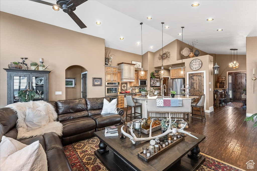 Living room featuring sink, high vaulted ceiling, ceiling fan with notable chandelier, and dark hardwood / wood-style flooring