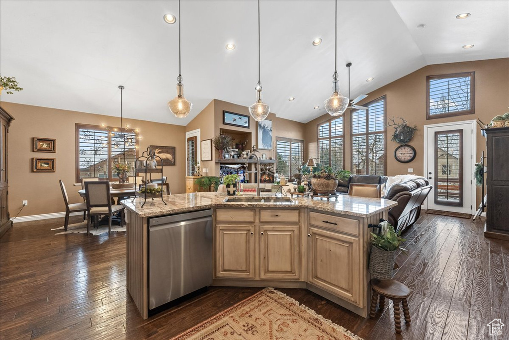 Kitchen with pendant lighting, an island with sink, light stone countertops, dark wood-type flooring, and dishwasher