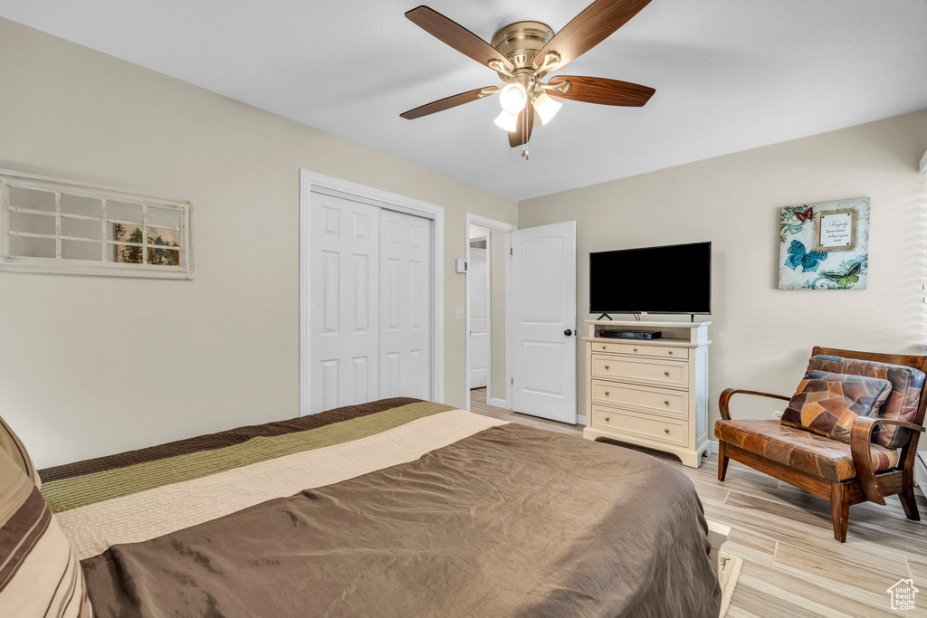 Bedroom with a closet, light hardwood / wood-style flooring, and ceiling fan