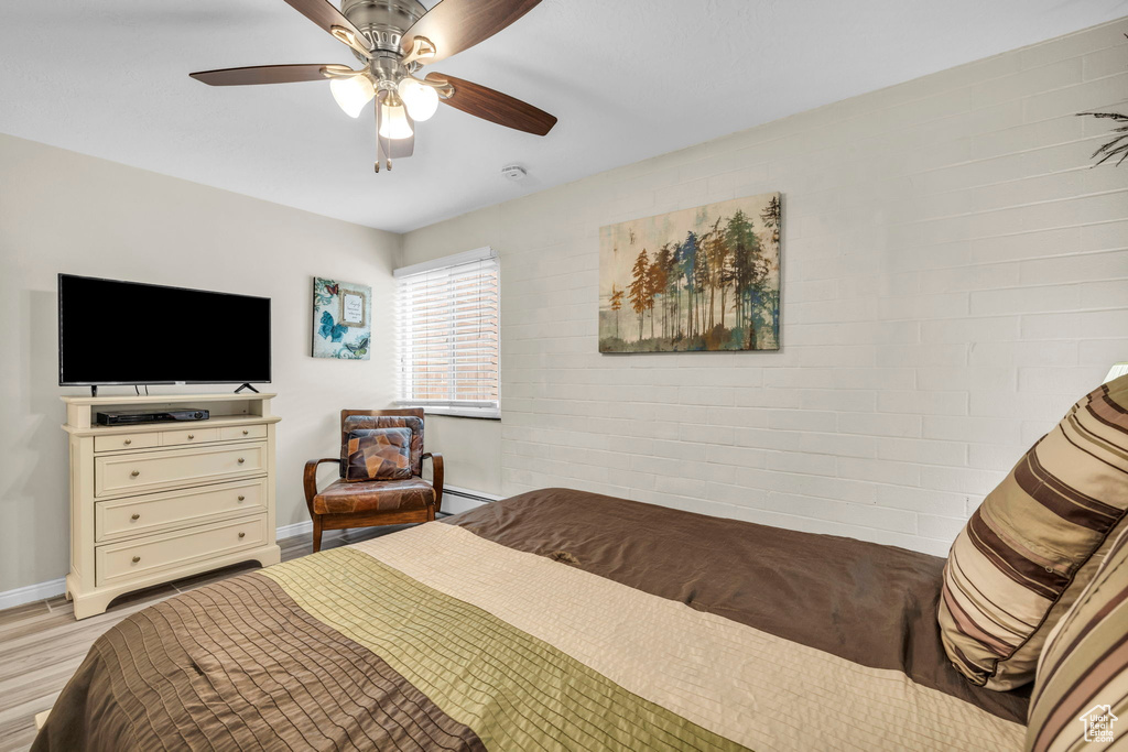 Bedroom featuring ceiling fan, baseboard heating, and light hardwood / wood-style floors