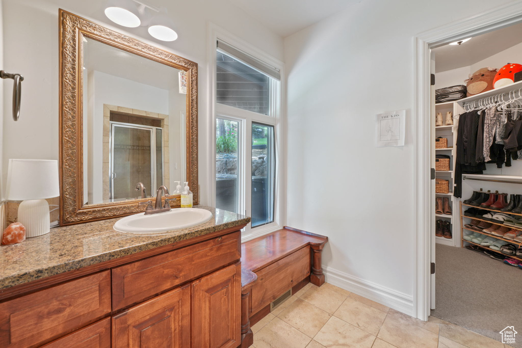 Bathroom with an enclosed shower, large vanity, and tile flooring