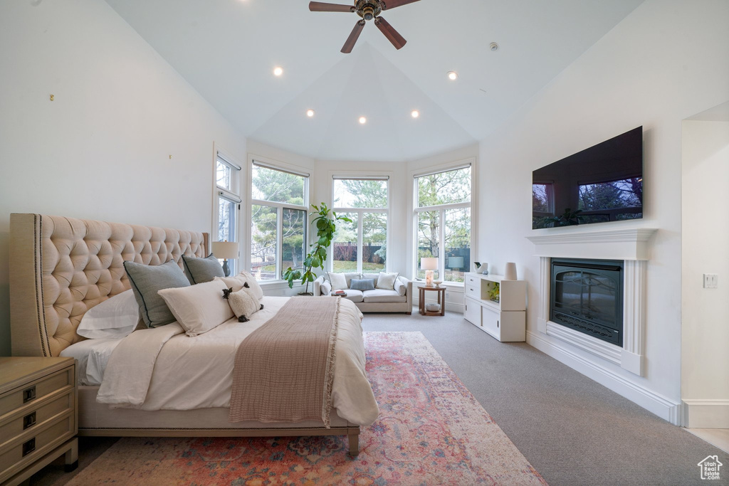 Bedroom with ceiling fan, high vaulted ceiling, and light colored carpet