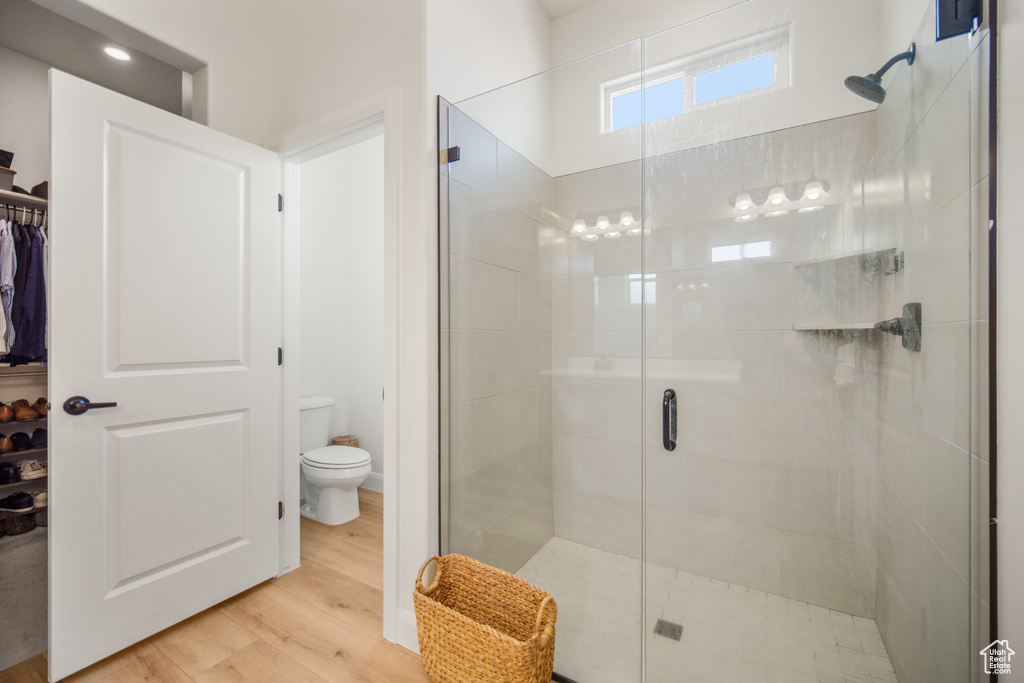 Bathroom with toilet, hardwood / wood-style floors, and a shower with door