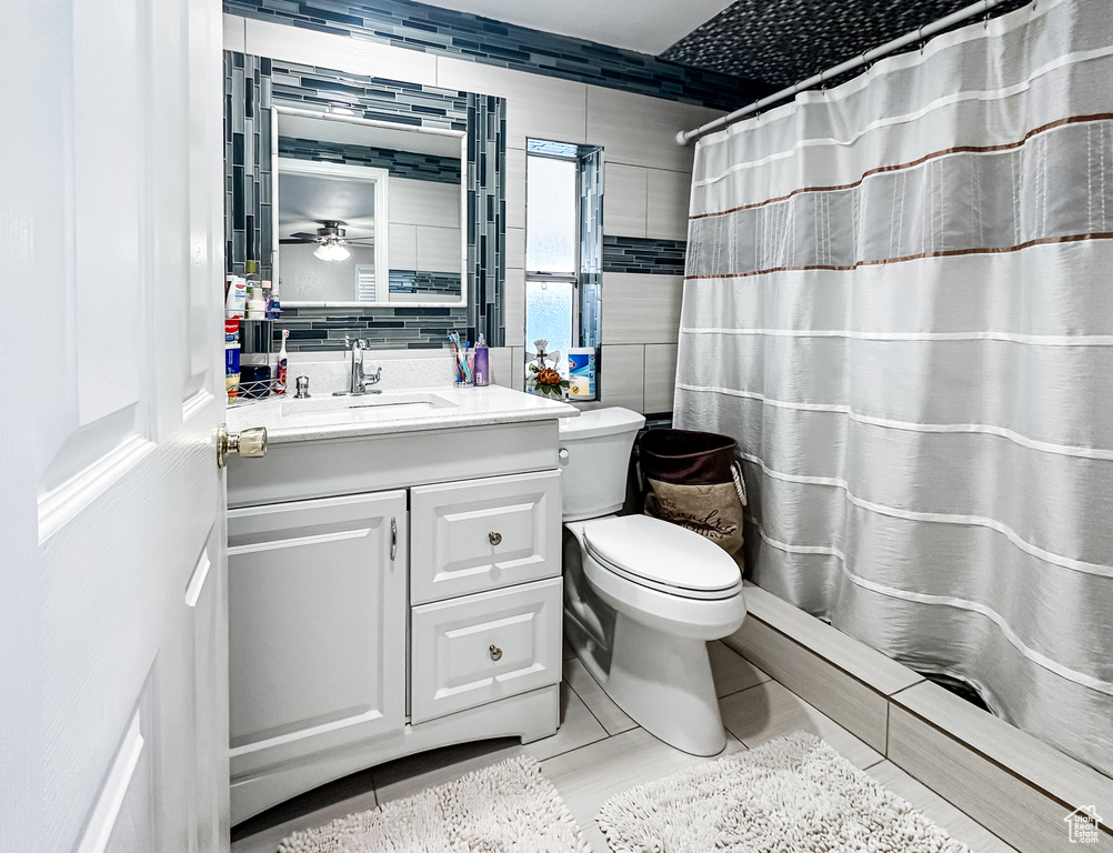 Bathroom featuring tile floors, tile walls, large vanity, and toilet