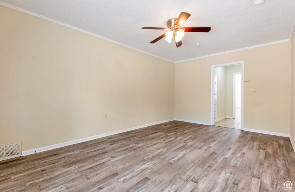 Empty room with ornamental molding, ceiling fan, and light hardwood / wood-style flooring