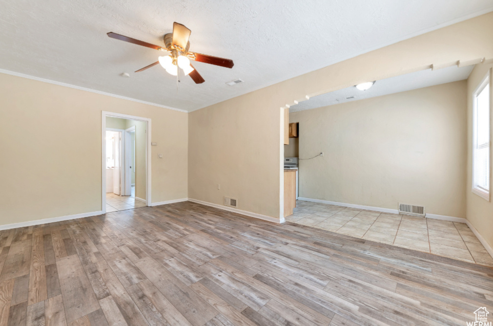 Unfurnished room with ornamental molding, light wood-type flooring, and ceiling fan