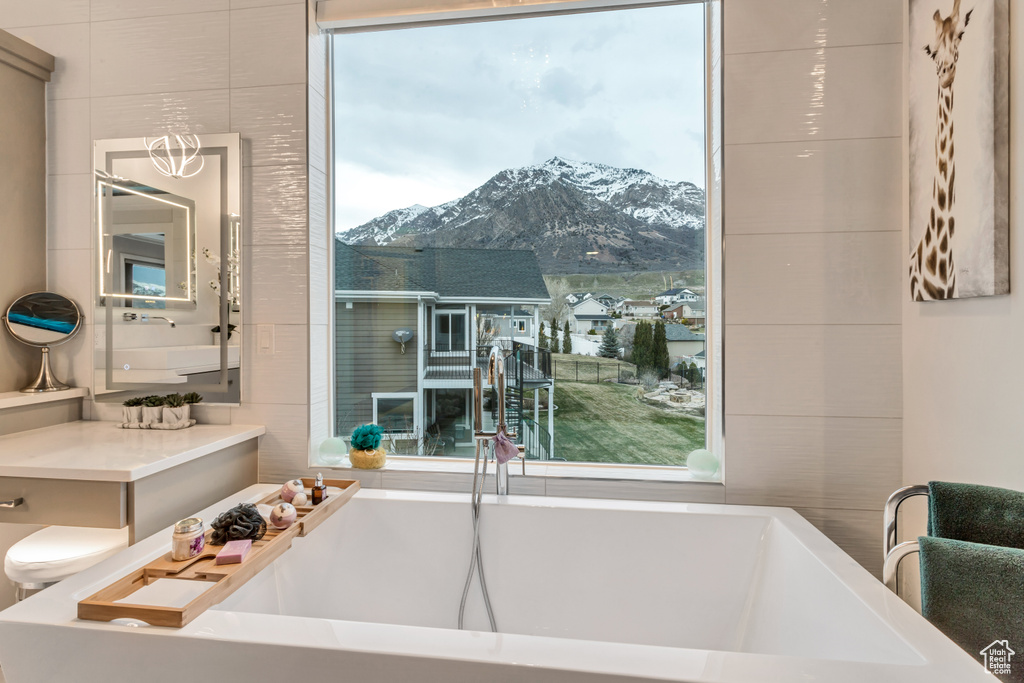 Bathroom with a mountain view, sink, an inviting chandelier, and a tub