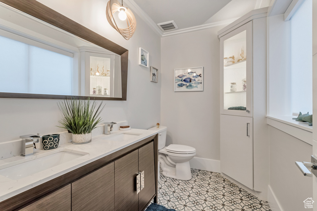Bathroom featuring crown molding, dual bowl vanity, toilet, and tile floors