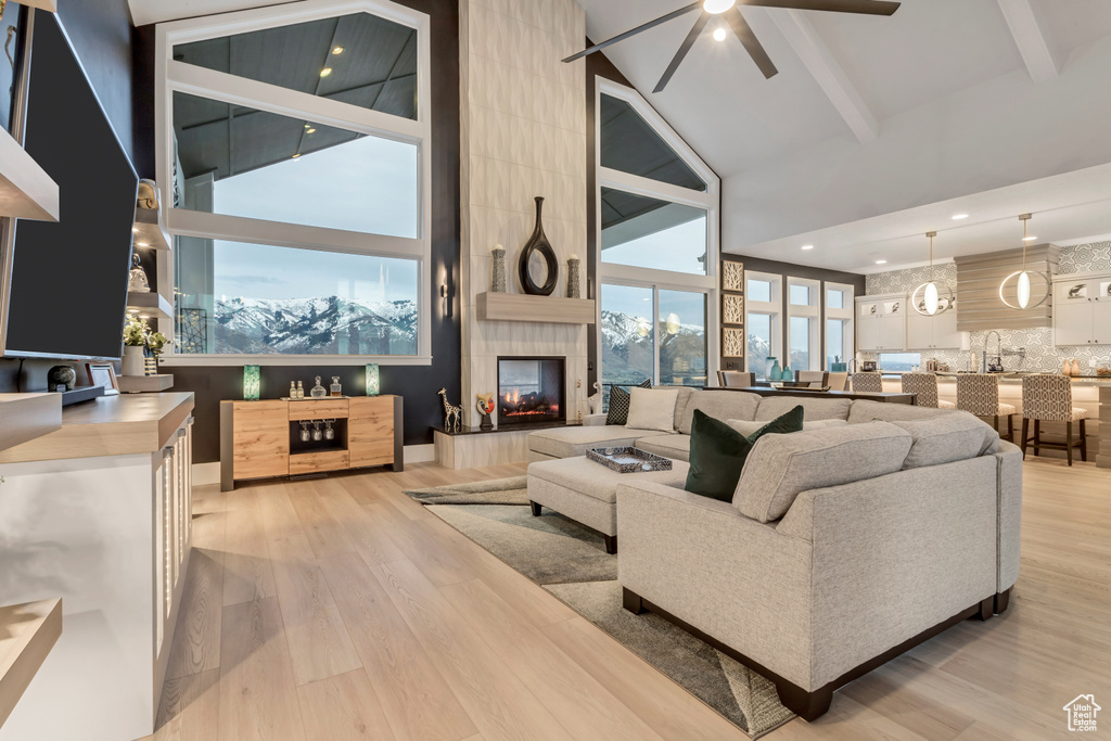 Living room with a tile fireplace, light hardwood / wood-style floors, and a towering ceiling