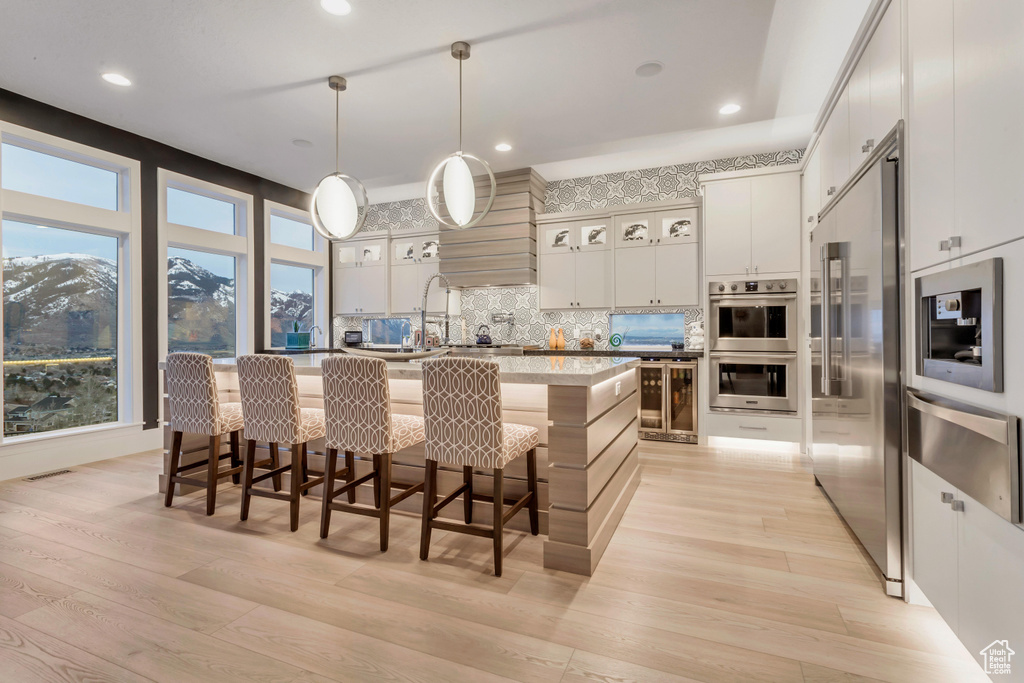 Kitchen featuring a kitchen island with sink, a kitchen bar, stainless steel appliances, and tasteful backsplash